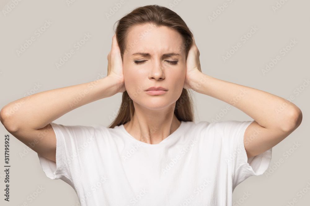 Annoyed young woman cover ears avoiding loud noises Annoyed young woman cover ears avoiding loud noises