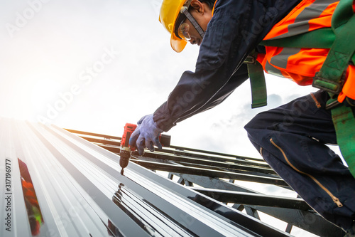[Construction roof] Roofer worker in protective uniform wear and gloves, Construction worker install new roof,Roofing tools,Electric drill used on new roofs with Metal Sheet.