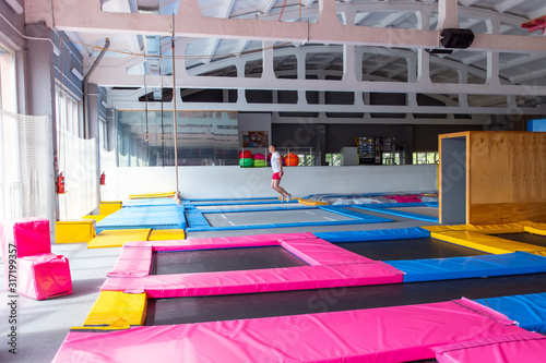 Fitness, fun, leisure and sport activity concept - Handsome happy man jumping on a trampoline indoors