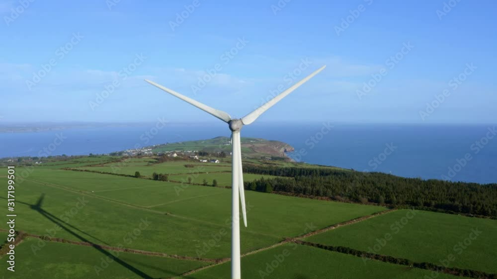 Aerial of Wind Turbine making clean energy in green field on sunny day Aerial of Wind Turbine making clean energy in green field on sunny day
