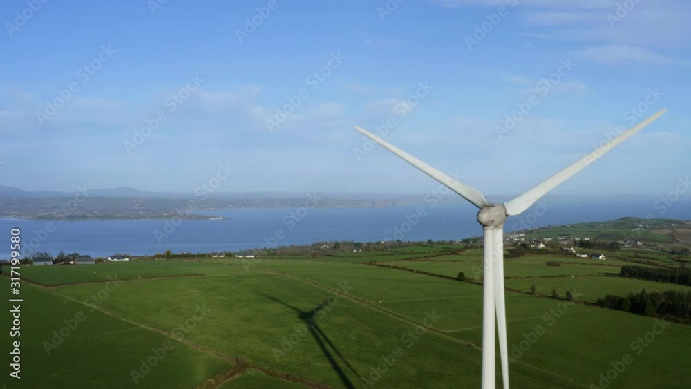Aerial of Windmill rear view at green field with sea background, truck left Aerial of Windmill rear view at green field with sea background, truck left