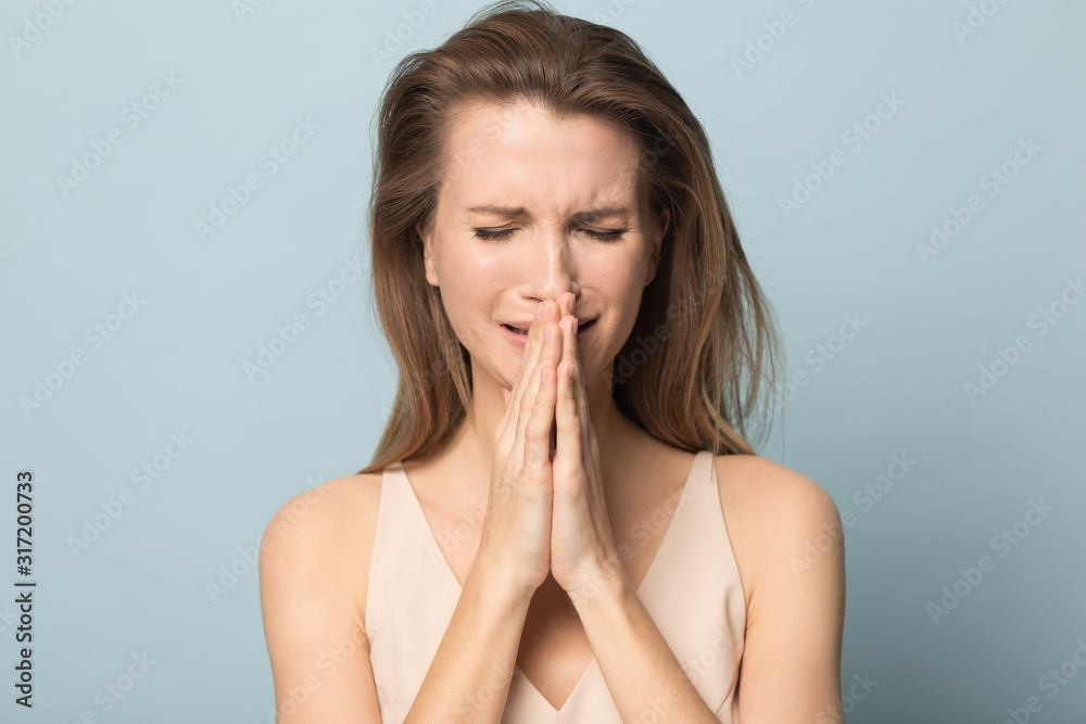 Depressed young woman crying holding hands in prayer Depressed young woman crying holding hands in prayer