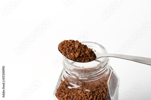 Instant coffee in spoon and a jar on a white background, granules closeup photo