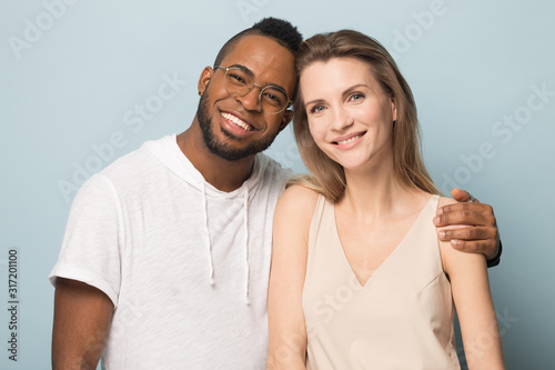 Portrait of multiracial couple hug looking at camera