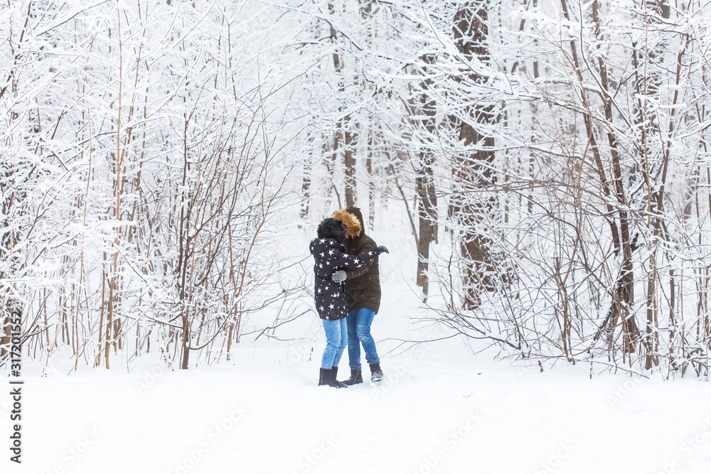Young couple in love have fun in the snowy forest. Active winter holidays.