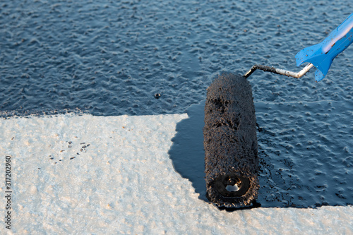 Worker applies bitumen mastic on the foundation