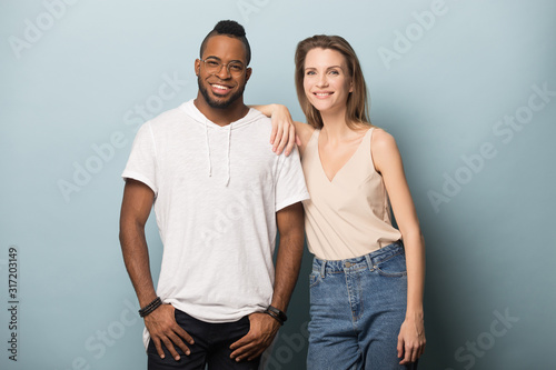 Smiling diverse man and woman posing for picture in studio