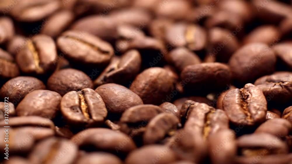 Close up of brown roasted coffee beans. Arabica coffee beans slowly spin. Premium quality light roasted coffee beans rotating. Close up of brown roasted coffee beans. Arabica coffee beans slowly spin. Premium quality light roasted coffee beans rotating.