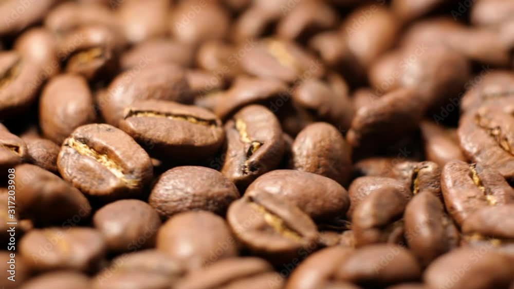 Close up of brown roasted coffee beans. Arabica coffee beans slowly spin. Premium quality light roasted coffee beans rotating. Close up of brown roasted coffee beans. Arabica coffee beans slowly spin. Premium quality light roasted coffee beans rotating.