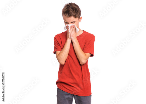 Portrait of unhealthy sick teen boy with napkin close his nose from allergy or rhinitis. Unhappy ill child suffering from running nose and sneezing and blow his nose isolated on white background.