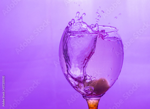 splashing water in a glass. pink spray. ice in a glass
