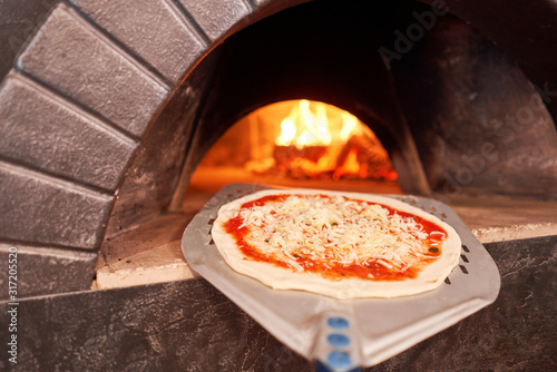 Raw billet for baking tasty margherita pizza in Traditional wood oven in Naples restaurant, Italy. Original neapolitan pizza. Red hot coal.