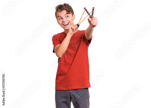 Fotografie Portrait of smiling teen boy holding slingshot in hands, isolated white background