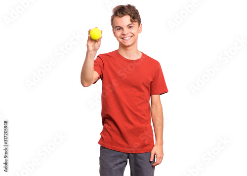 Portrait of happy teen boy holding tennis ball, isolated white background. Smiling teenager showing yellow tennis ball. Happy child. Sport, exercise, training concept.
