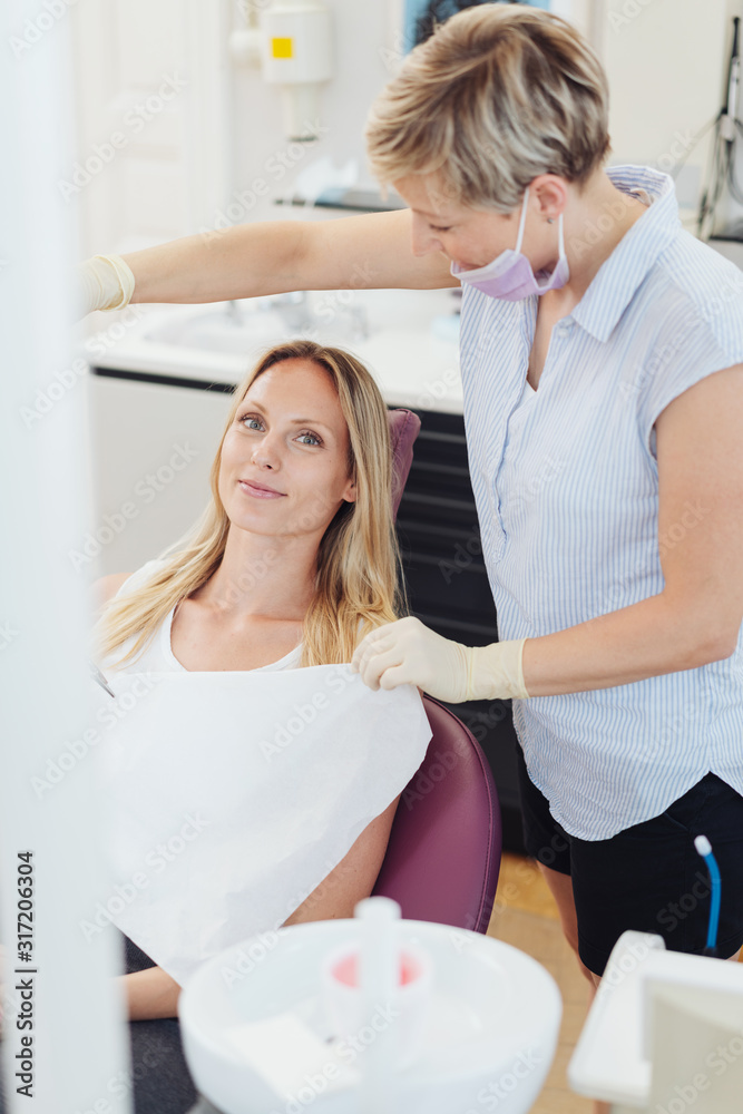 Dental nurse removing a bib from a female patient
