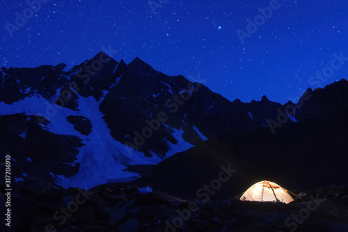Starry night mountain landscape with glowing tent.