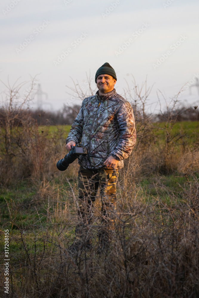 Professional wildlife photographer in camouflage clothing Professional wildlife photographer in camouflage clothing