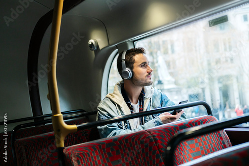 A boy listens to music in headphones and uses the mobile phone on a bus