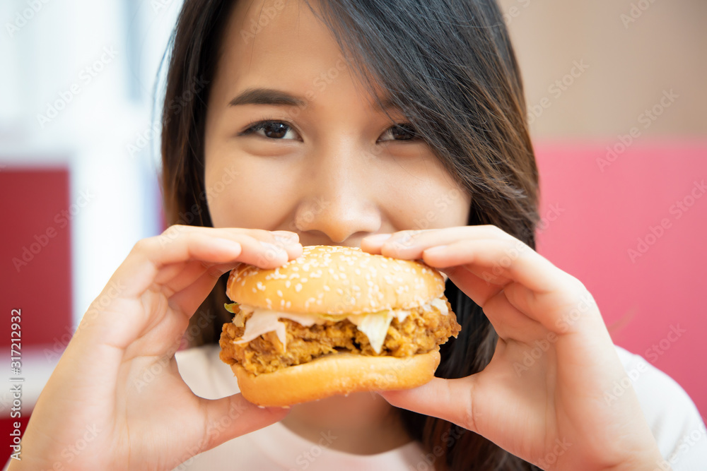 hungry woman looking, eating fried chicken burger; concept of delicious food, junk food, fast food, health care, eating habit, crispy tasty fried chicken burger; asian young adult woman model hungry woman looking, eating fried chicken burger; concept of delicious food, junk food, fast food, health care, eating habit, crispy tasty fried chicken burger; asian young adult woman model