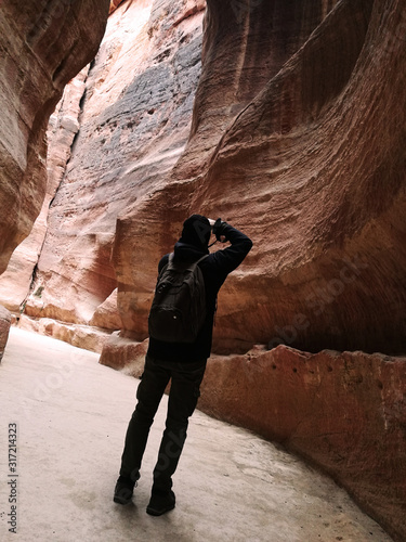 Estrecho cañón de rocas rojas con turista sacando fotos