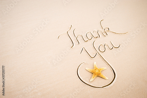 Thank You message handwritten in calligraphy with a starfish on a smooth stretch of beach with sand copy space
