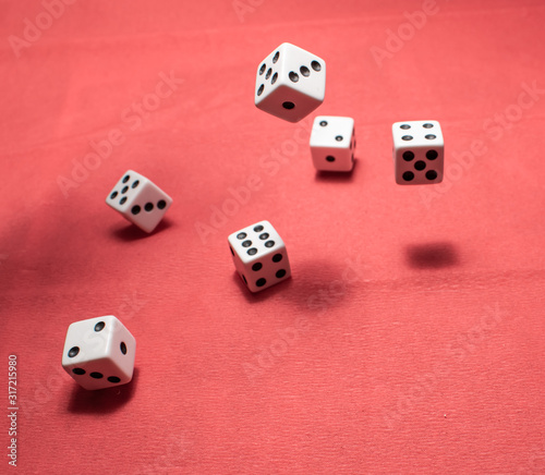 Hand throwing dice  hoping for the best odds. Six dice on red background