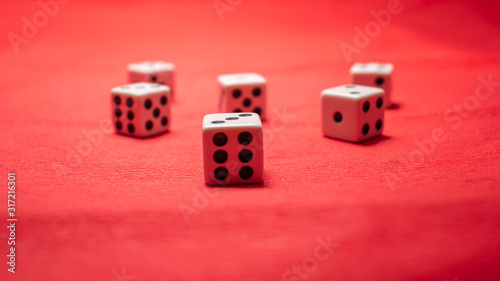 Hand throwing dice, hoping for the best odds. Six dice on red background