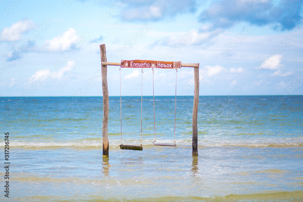 beach swing in the water with blue sky and clouds beach swing in the water with blue sky and clouds