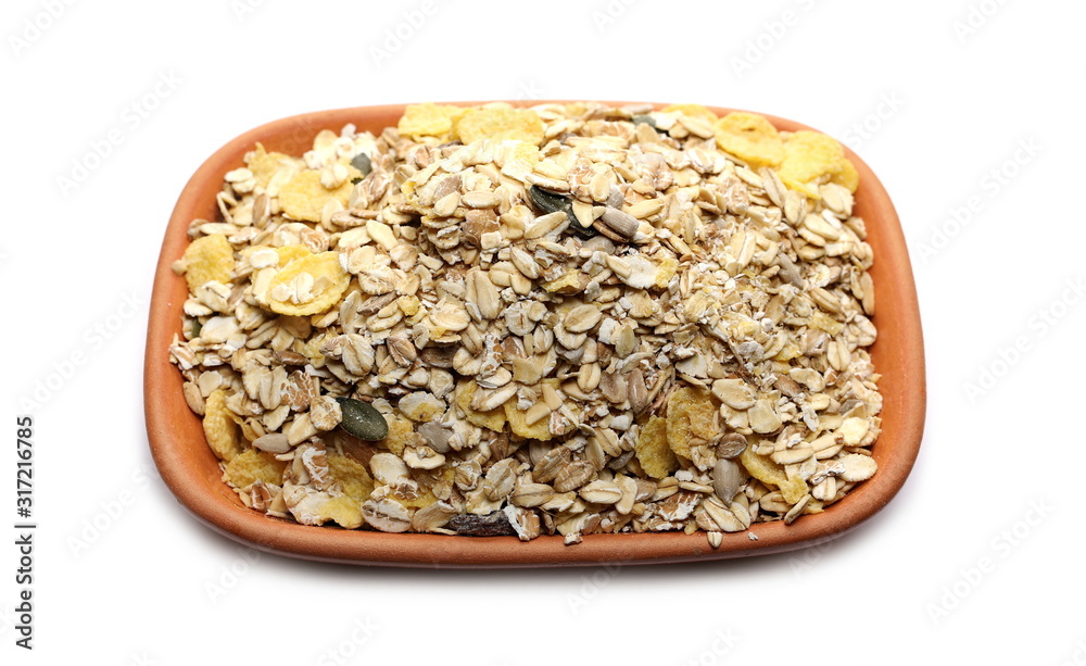 Muesli mixture of wholegrain foods, cereals, seeds and raisins in clay bowl isolated on white background Muesli mixture of wholegrain foods, cereals, seeds and raisins in clay bowl isolated on white background