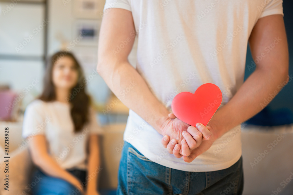 young man holding red paper heart behind his back for his beautiful wife, happy romantic unniversary, saint valentine's day young man holding red paper heart behind his back for his beautiful wife, happy romantic unniversary, saint valentine's day