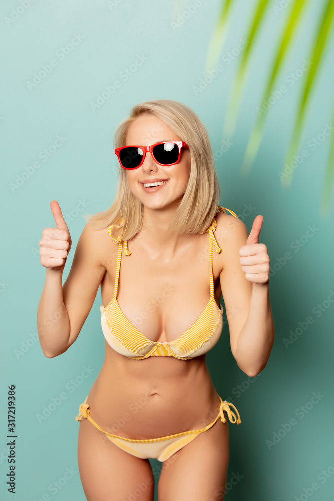 Beautiful blonde woman in bikini with a palm branch