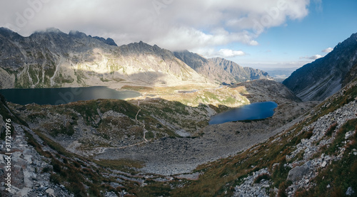 Scenic view of the Tatra Mountains on a sunny summer day, with green valleys, rugged peaks, and a blue sky.