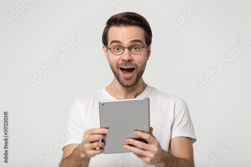 Excited young man holding digital gadget portrait.