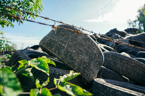 Old rubber tires are stacked up in a pile behind a fence