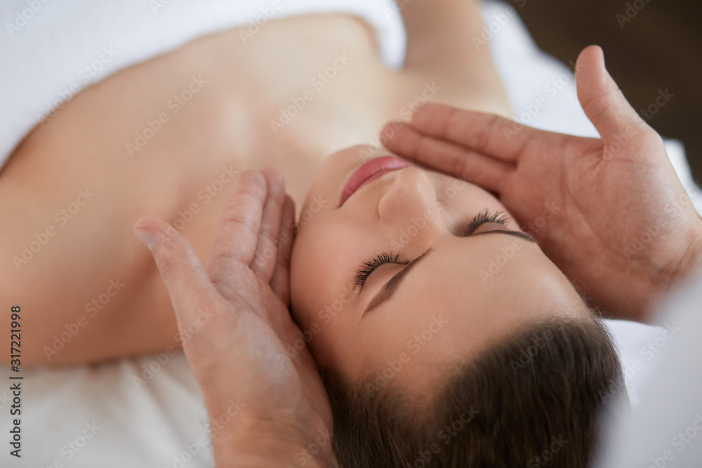 Young beautiful woman enjoying anti-aging facial massage.Male therapist making head massage to female client.Professional masseur.Relaxation,beauty,spa,body and face treatment concept. Young beautiful woman enjoying anti-aging facial massage.Male therapist making head massage to female client.Professional masseur.Relaxation,beauty,spa,body and face treatment concept.