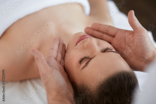 Young beautiful woman enjoying anti-aging facial massage.Male therapist making head massage to female client.Professional masseur.Relaxation,beauty,spa,body and face treatment concept. © YURII MASLAK