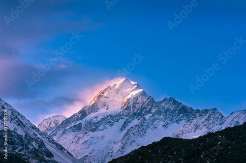 Mountain peak with snow and fog at sunset with colorful sunlight