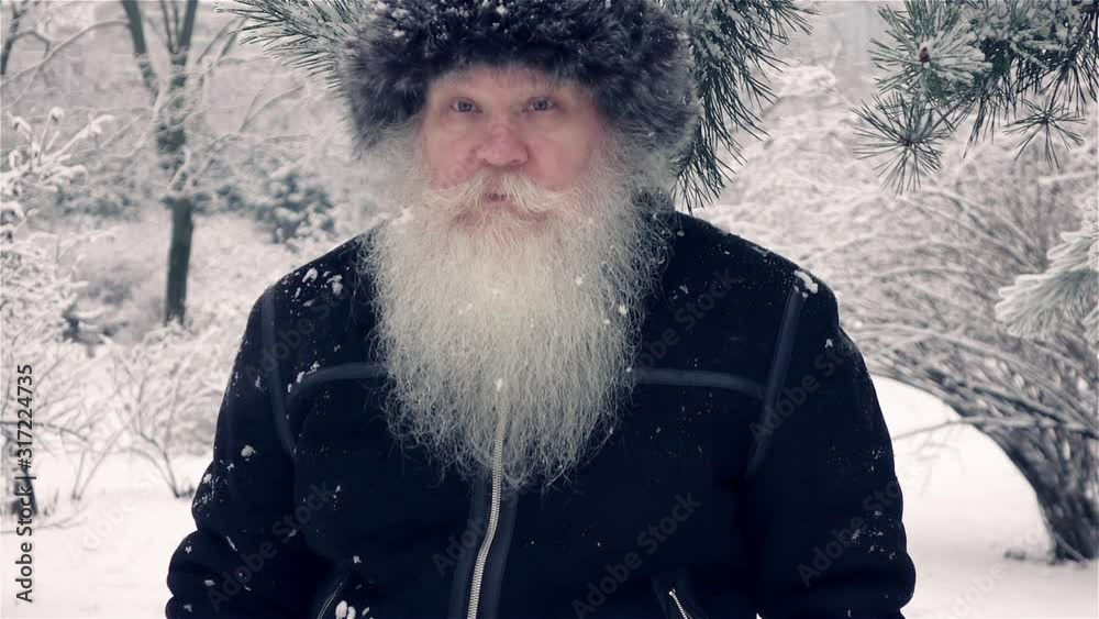 Attractive elderly man moving on camera in slow motion. Closeup winter portrait at snow-covered forest. Healthy cheerful senior retired person. Attractive elderly man moving on camera in slow motion. Closeup winter portrait at snow-covered forest. Healthy cheerful senior retired person.