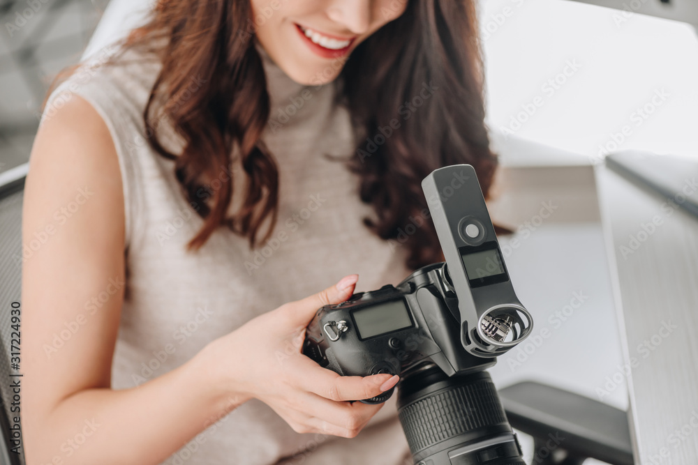 cropped view of happy art editor holding digital camera cropped view of happy art editor holding digital camera