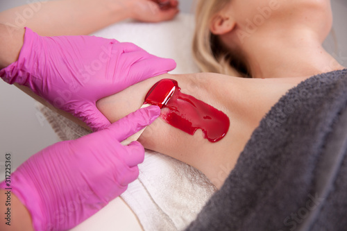 Waxing woman armpit with spatula. Salon wax beautician epilation procedure. Waxing female body for hair removal by therapist close up. Smooth underarm concept.
