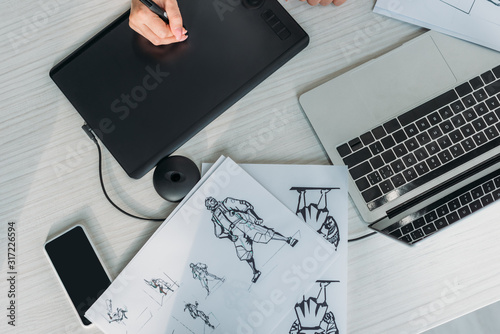 top view of animator using digital tablet near sketches