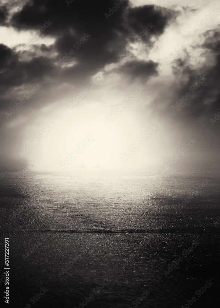 Dramatic black and white background. Cloudy night sky, moonlight, reflection on the pavement. Smoke and fog on a dark street at night. Dramatic black and white background. Cloudy night sky, moonlight, reflection on the pavement. Smoke and fog on a dark street at night.
