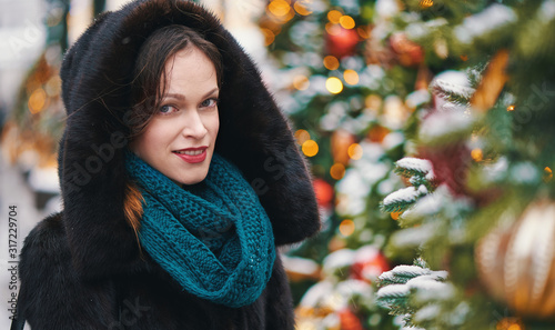 Happy young woman near the Christmas treeon a street photo