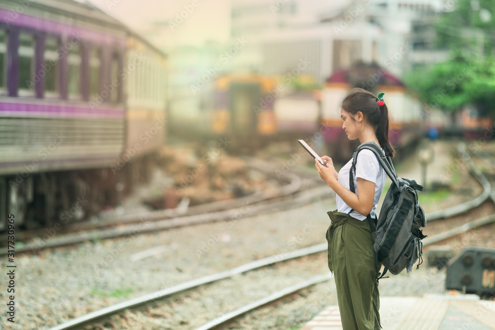 Obraz premium asian girl checking map on phone with backpack, travel by train, destination nature trip in summer