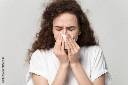 Close up portrait young unhealthy woman wiping runny nose.