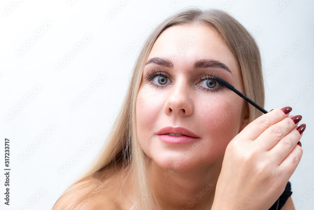 Beauty portrait of girl with perfect nude make-up. Painting eyelashes with mascara. Turned aside. Beauty salon. Head and shoulders, studio, indoors. Beauty portrait of girl with perfect nude make-up. Painting eyelashes with mascara. Turned aside. Beauty salon. Head and shoulders, studio, indoors.