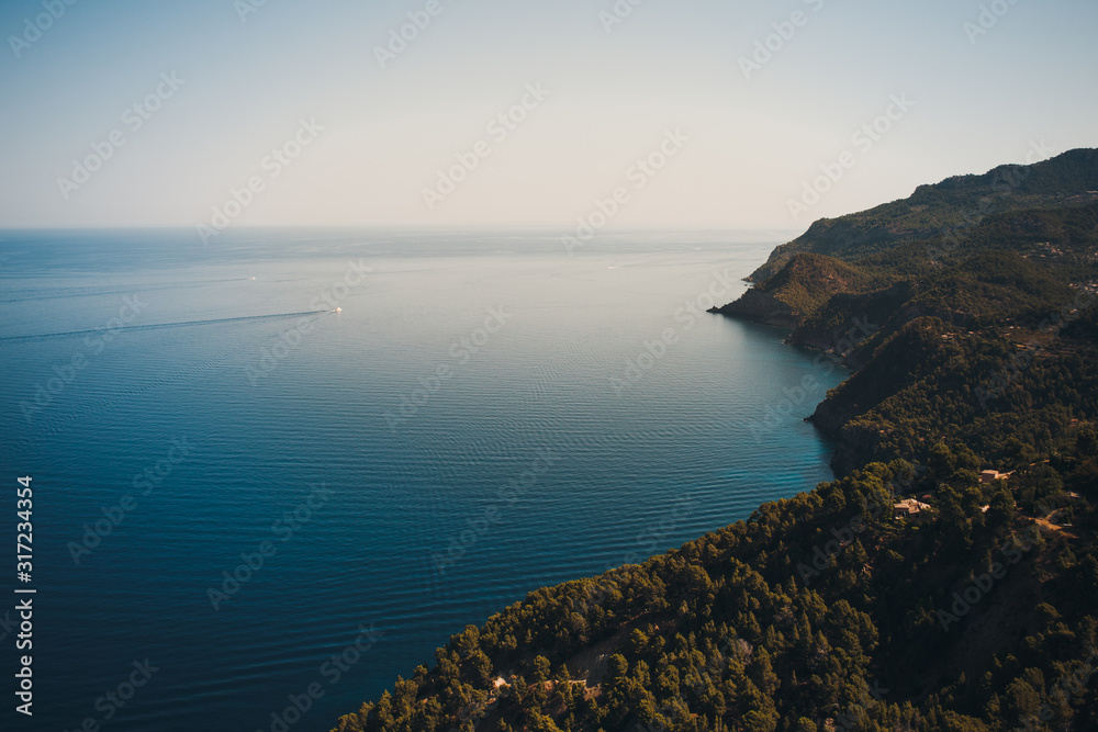 Hilly coast of Majorca. in the background a small boat on the sea. summer scenery.