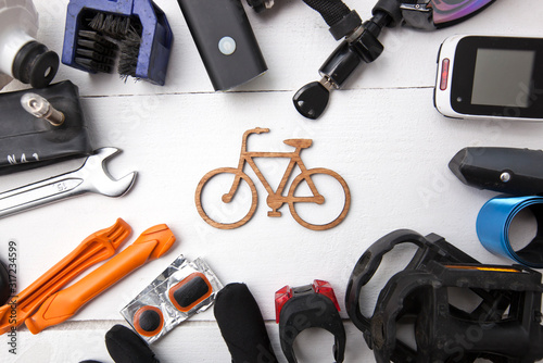 A lot of different bicycle accessories lying on wooden table around a little bicycle icon