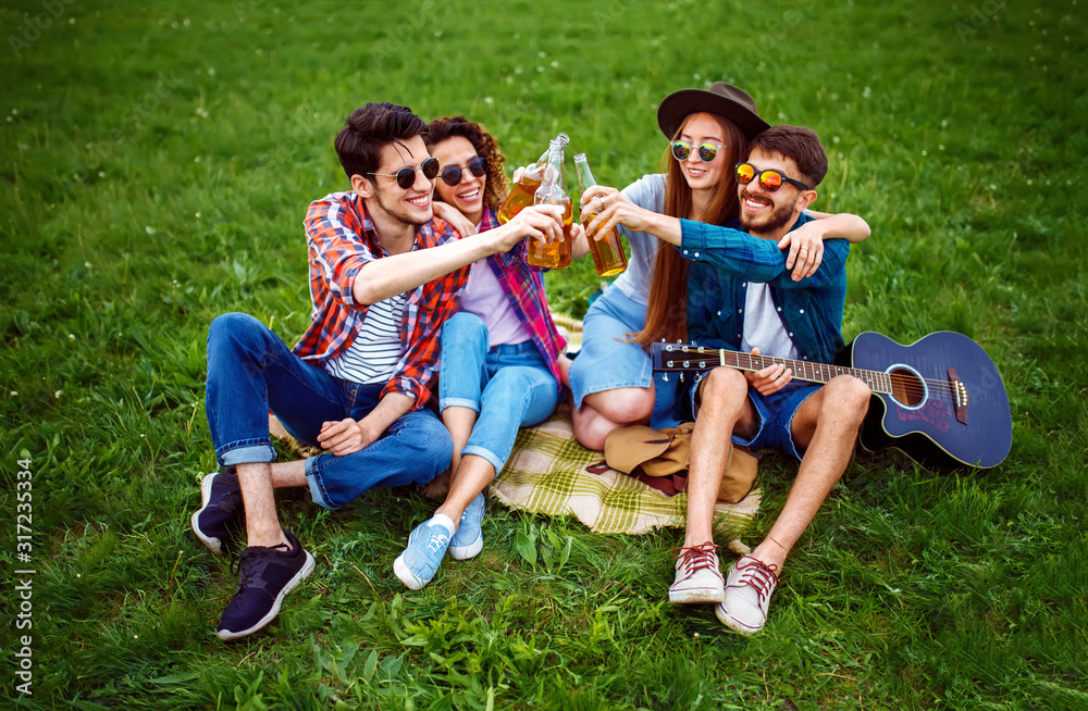 Happy friends spending free time together in park sitting on grass, drinking beer and chatting. Group of young people enjoying party n the summer park. Rest, fun, summer concept. Happy friends spending free time together in park sitting on grass, drinking beer and chatting. Group of young people enjoying party n the summer park. Rest, fun, summer concept.