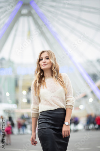 Gorgeus blonde woman in leather skirt posing on the ferris wheel background
